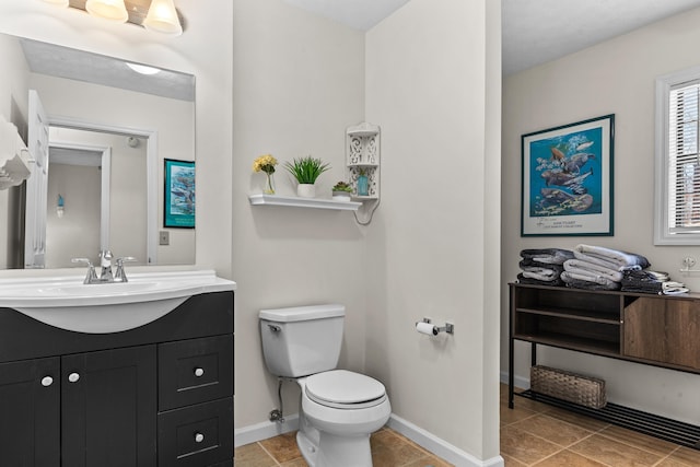 bathroom featuring toilet, baseboards, and vanity