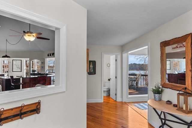 hall with light wood-style flooring and baseboards