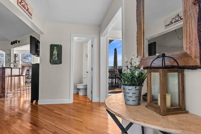 corridor with baseboards and wood finished floors