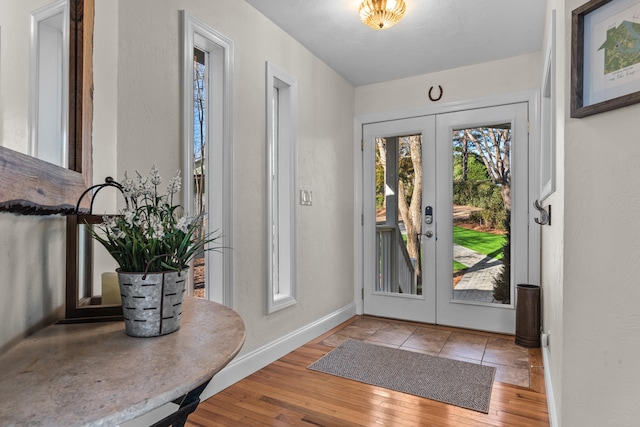 entryway with french doors, light wood-style flooring, and baseboards