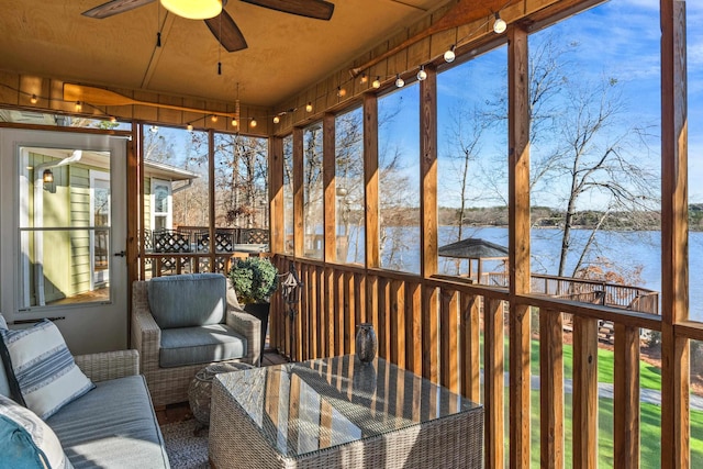 sunroom / solarium featuring a water view and a ceiling fan