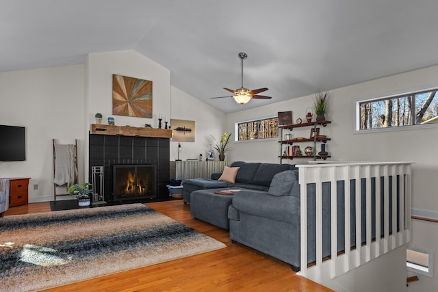 living area with lofted ceiling, a tile fireplace, wood finished floors, and a wealth of natural light