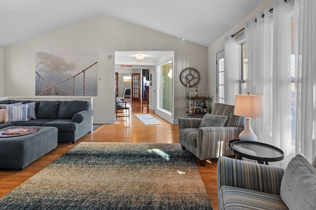 living room featuring baseboards, vaulted ceiling, and wood finished floors