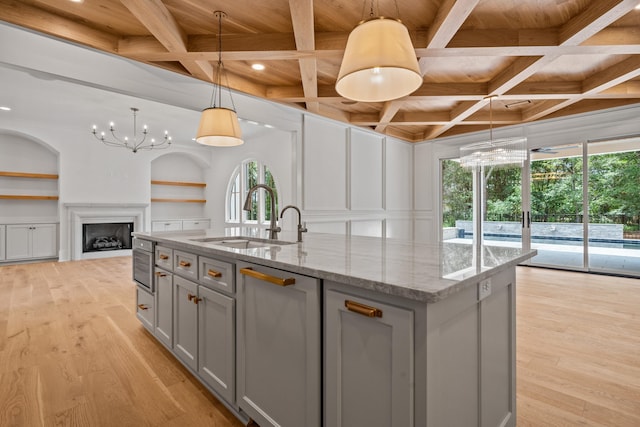 kitchen with light wood-style flooring, built in features, a sink, and gray cabinetry