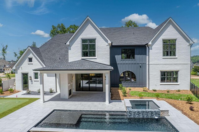 rear view of property featuring board and batten siding, a patio area, fence, and an in ground hot tub