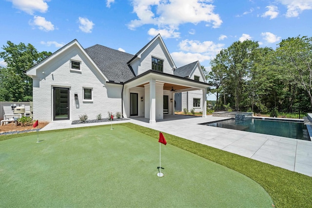 rear view of property with a fenced in pool, brick siding, a patio, a shingled roof, and ceiling fan