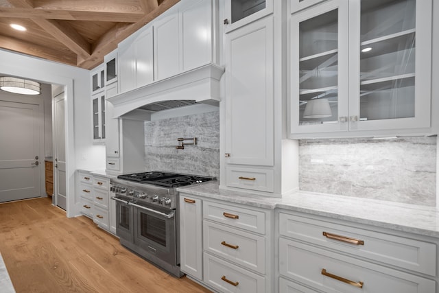 kitchen with light stone counters, range with two ovens, light wood-style flooring, and white cabinets