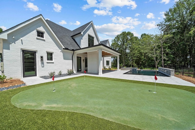 back of house with a fenced in pool, roof with shingles, brick siding, a patio area, and fence