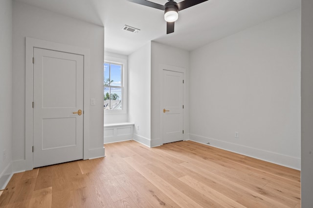 interior space featuring light wood-style flooring, visible vents, ceiling fan, and baseboards