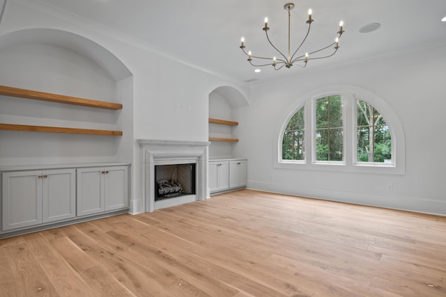 unfurnished living room with built in features, light wood-style floors, a fireplace, and ornamental molding