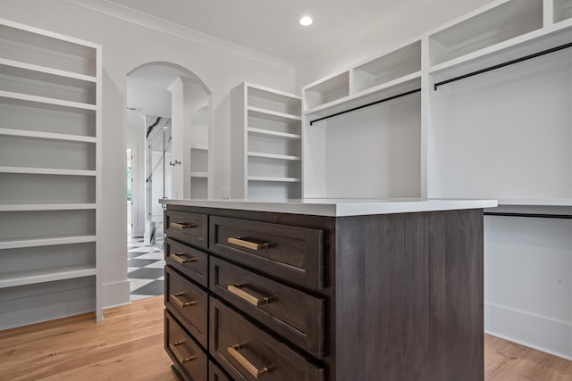 spacious closet with light wood-type flooring and arched walkways