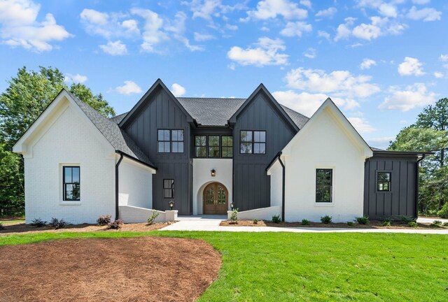 modern farmhouse featuring brick siding, a shingled roof, board and batten siding, and a front yard