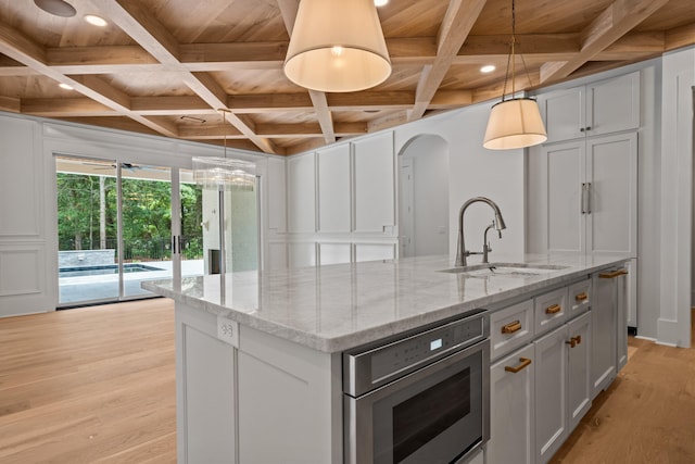 kitchen featuring light wood finished floors, wood ceiling, a sink, an island with sink, and coffered ceiling