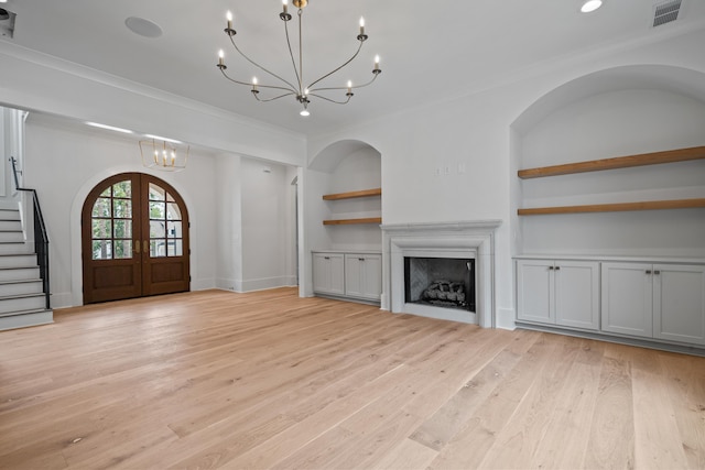 unfurnished living room with light wood finished floors, french doors, ornamental molding, and built in features