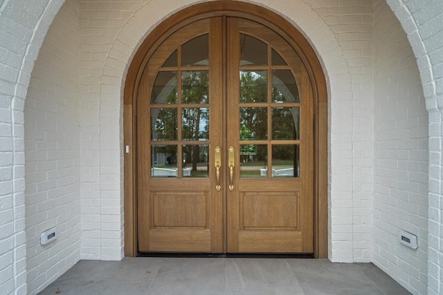 entrance to property featuring french doors and brick siding