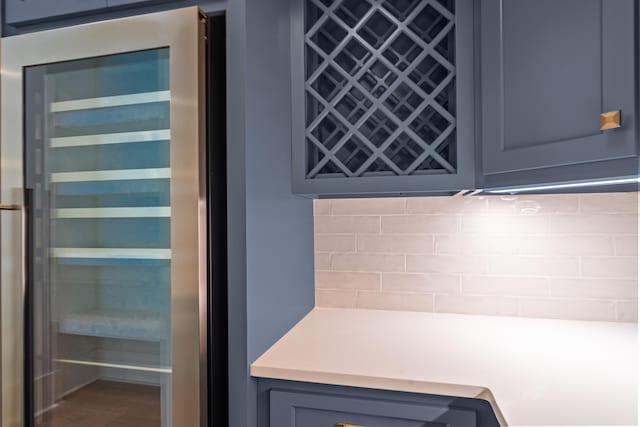 interior space featuring beverage cooler, light countertops, backsplash, and wood finished floors