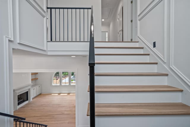 stairs featuring wood finished floors, a towering ceiling, and attic access