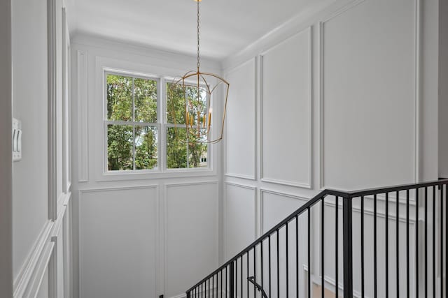 staircase featuring an inviting chandelier and a decorative wall