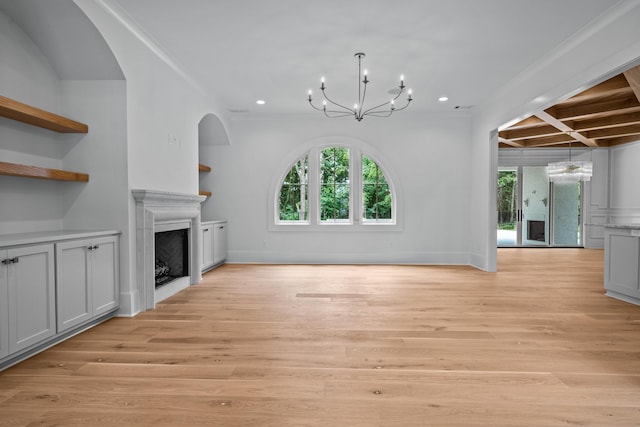 unfurnished living room featuring a healthy amount of sunlight, light wood finished floors, a fireplace, and a chandelier