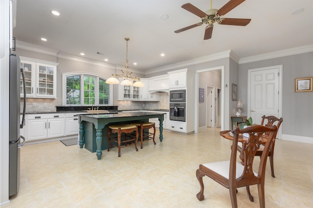 1320 Dejarnet Pl, Greensboro, GA 30642 - kitchen with stainless steel appliances, dark countertops, a breakfast bar area, tasteful backsplash, and crown molding