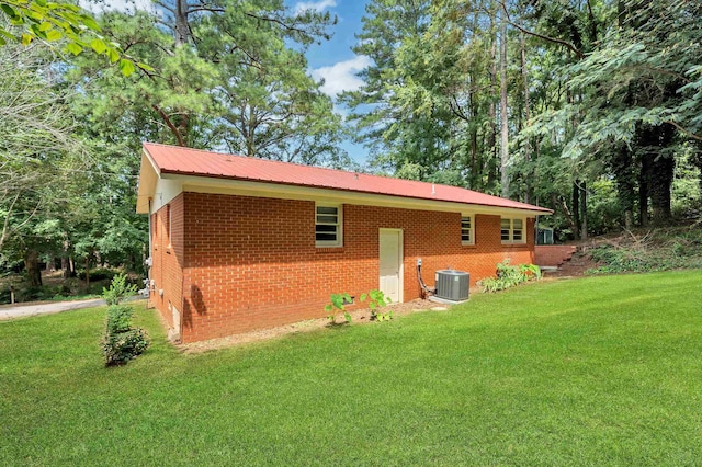 rear view of property featuring central AC unit and a lawn