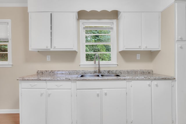 kitchen featuring white cabinetry, sink, and ornamental molding