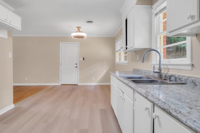 kitchen with a healthy amount of sunlight, sink, white cabinets, and light hardwood / wood-style flooring