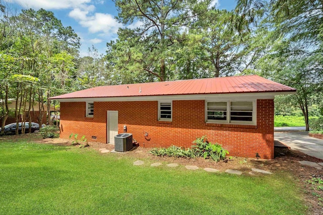 rear view of property with central AC and a lawn