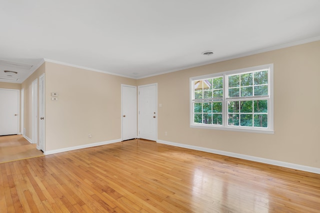 spare room with crown molding and light wood-type flooring