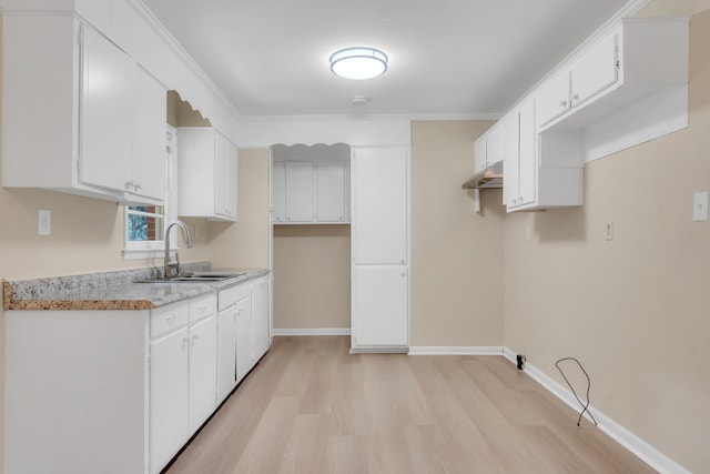 kitchen with white cabinetry, sink, light stone counters, light hardwood / wood-style floors, and crown molding