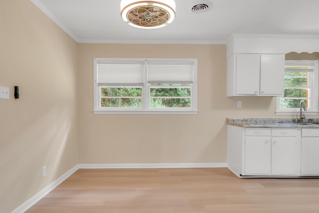 kitchen featuring ornamental molding, sink, white cabinets, and light wood-type flooring