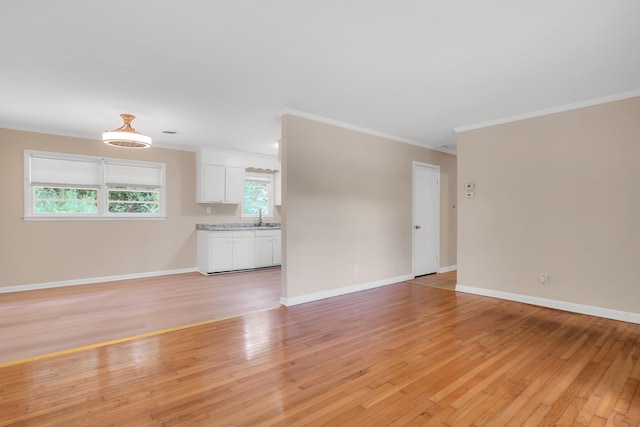 unfurnished living room featuring sink, crown molding, and light hardwood / wood-style floors