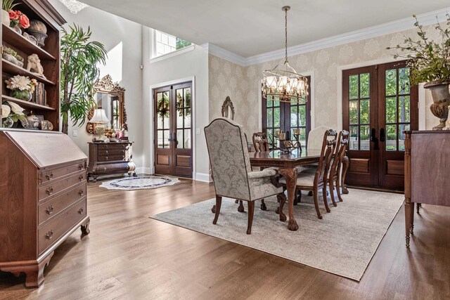 dining room with french doors, crown molding, light hardwood / wood-style floors, and a notable chandelier