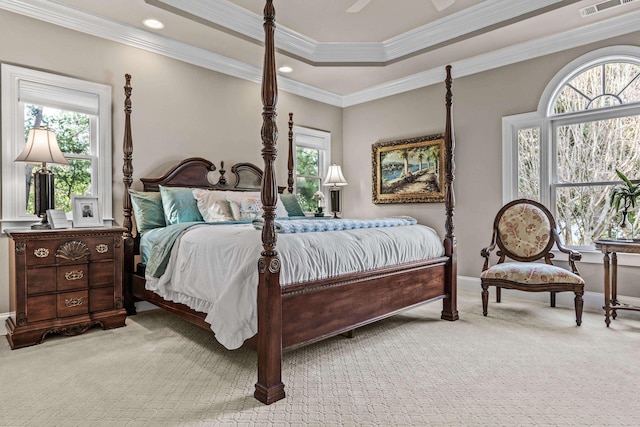 bedroom with multiple windows, ornamental molding, light colored carpet, and a tray ceiling