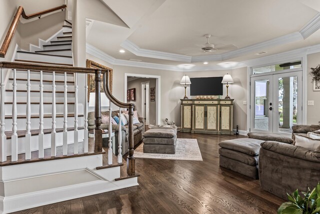 living room with ceiling fan, a tray ceiling, ornamental molding, dark hardwood / wood-style flooring, and french doors