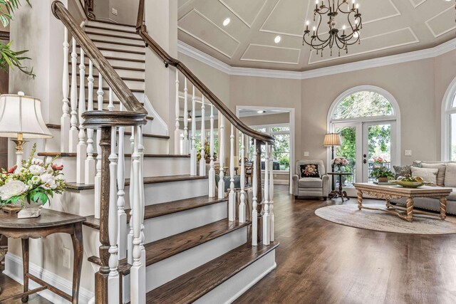 entrance foyer featuring crown molding, an inviting chandelier, coffered ceiling, dark hardwood / wood-style flooring, and french doors