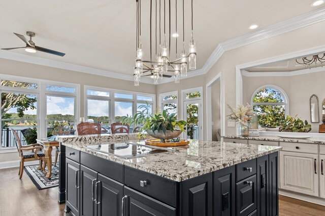 kitchen featuring black electric cooktop, plenty of natural light, ornamental molding, and a center island