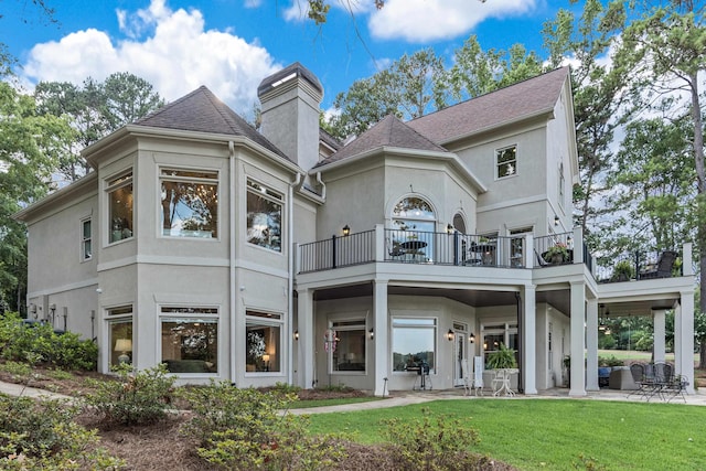 rear view of property with a balcony, a yard, and a patio area