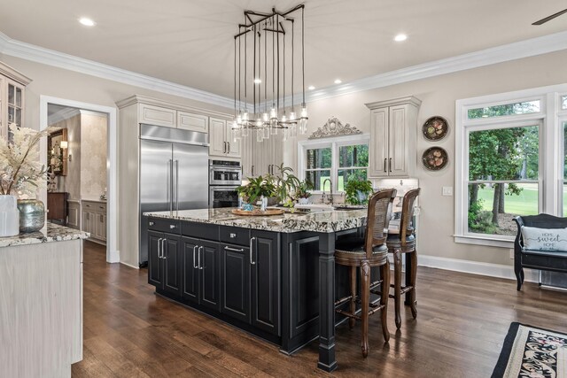 kitchen featuring ornamental molding, an island with sink, and appliances with stainless steel finishes