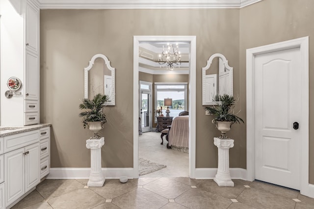 tiled entryway with ornamental molding and a chandelier