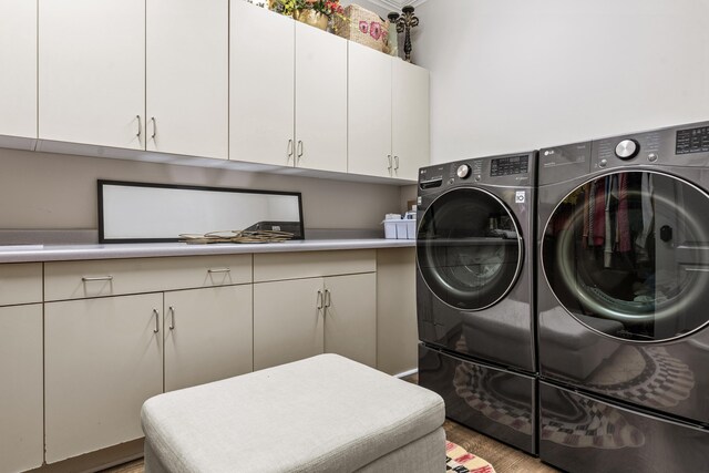 laundry room featuring cabinets, wood-type flooring, and washing machine and dryer