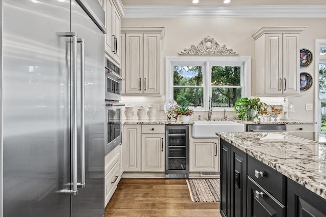 kitchen with appliances with stainless steel finishes, sink, beverage cooler, dark hardwood / wood-style flooring, and crown molding