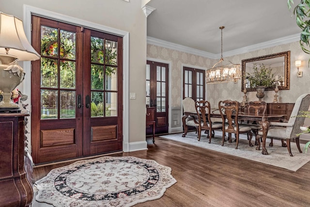 foyer entrance with ornamental molding, dark wood-type flooring, an inviting chandelier, and french doors