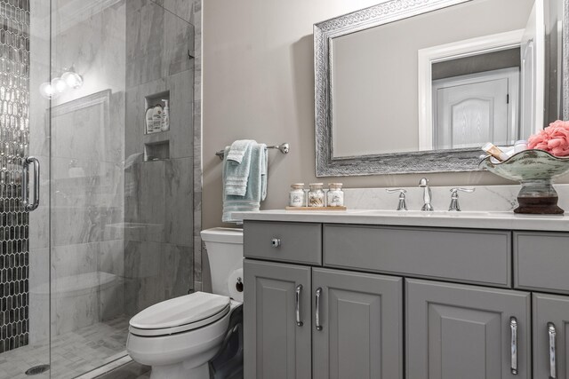 bathroom with vanity, toilet, and a shower with door