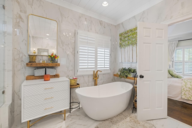 full bathroom featuring ornamental molding, marble finish floor, a freestanding tub, and ensuite bath