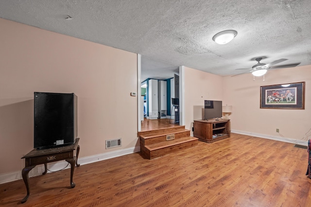 living room with wood finished floors, visible vents, a ceiling fan, and baseboards