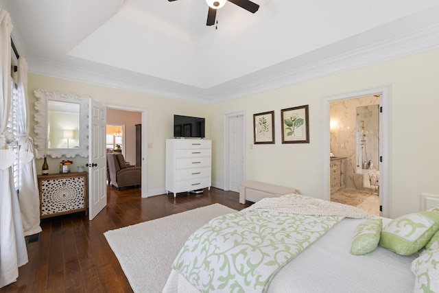bedroom with dark wood finished floors, ornamental molding, ceiling fan, ensuite bathroom, and a tray ceiling