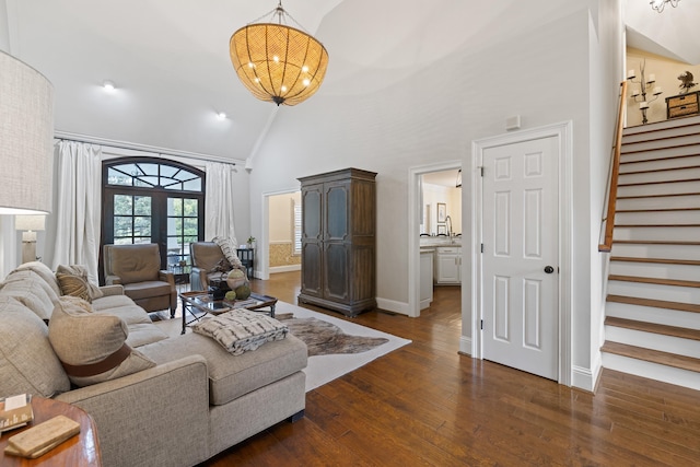 living area with a notable chandelier, stairway, baseboards, dark wood-type flooring, and high vaulted ceiling