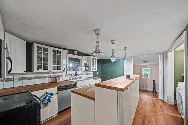 kitchen featuring stainless steel dishwasher, butcher block counters, a sink, black range with electric stovetop, and a center island