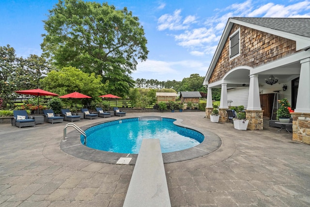 outdoor pool featuring a patio, fence, and a diving board